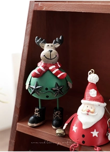 Close-up of hand-painted reindeer and Santa metal figurines on a wooden shelf