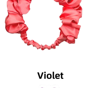 Close-up of pleated satin headband in coral pink with smooth elastic texture