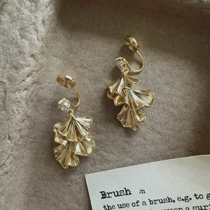 Detailed view of golden leaf clip earrings with rhinestones and textured petal design