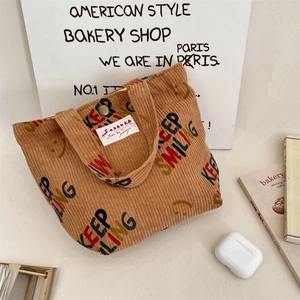 Detailed texture of brown corduroy tote with Keep Smiling print and metal snap button
