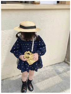 Detail of child wearing navy dress with a yellow pearl strap drawstring handbag