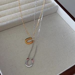 Detail view of gold and silver U-shaped horseshoe pendants on velvet jewelry tray