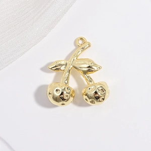Detailed top view of a gold cherry pendant with hammer texture on a white mesh background