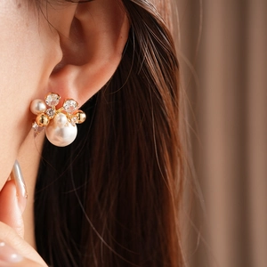 Close-up of luxury flower-shaped earrings featuring pearls and sparkling cubic zirconia stones