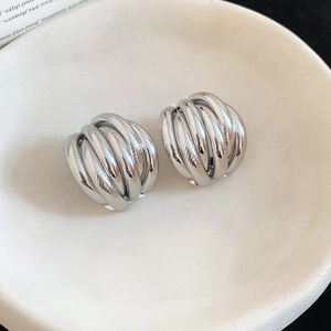 Macro detail of silver layered croissant stud earrings on white ceramic plate