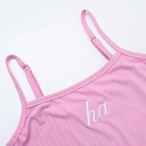 Detailed macro view of pink ribbed knit camisole featuring white ha letter embroidery