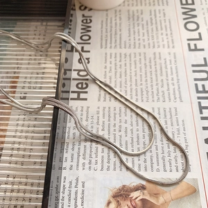 Detail shot of silver titanium square snake chain necklace on a vintage paper background