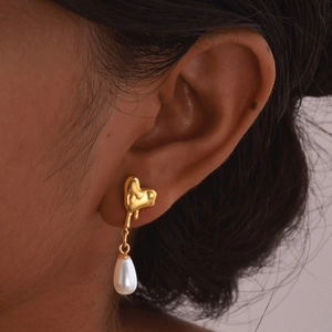 Elegant gold heart lava earrings with teardrop faux pearls on a female model
