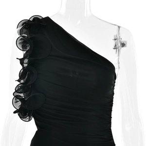 Détail de la fleur en maille 3D et de la texture froncée sur la robe noire à une épaule