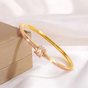 Elegant gold titanium steel bracelet featuring pink rhinestones on a white silk background