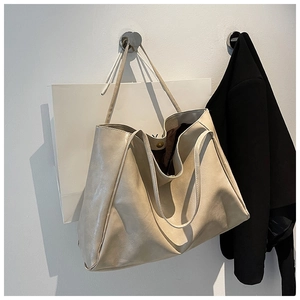 Detail view of large cream tote bag showing soft leather texture and magnetic closure