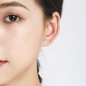 Polished S925 sterling silver heart stud earrings worn by a female model