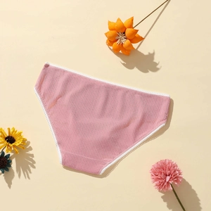 Detail shot of pink ribbed knit panties with white lace edges on floral background