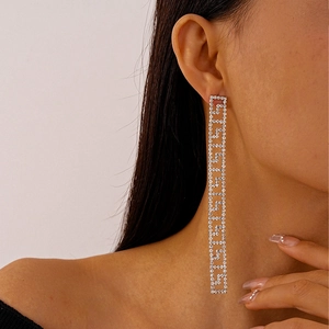 Detail shot of long geometric Greek key drop earrings with shiny rhinestones on a model