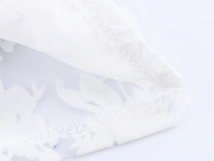 Macro shot of fine white mesh fabric with elegant floral embroidery and stitching detail
