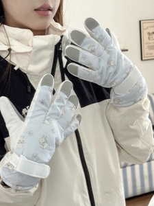 Detail of light blue ski gloves with pink rabbit patterns and adjustable wrist straps