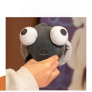 Détail d'un porte-clés mouche en peluche grise avec de grands yeux tenu à la main