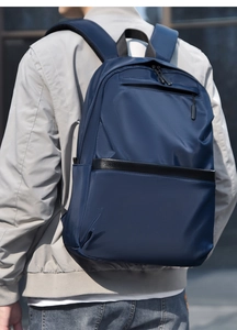 Close-up of a man wearing a dark blue minimalist laptop backpack in an urban setting