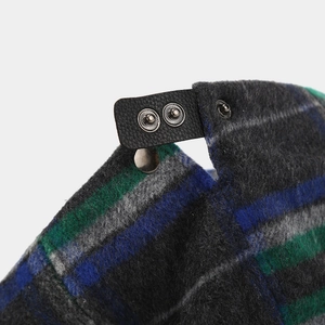 Detail of adjustable leather strap and metal snaps on retro plaid wool newsboy hat