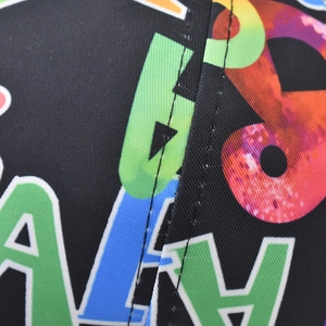 Macro view of colorful letter prints and double-needle stitching on a baseball cap