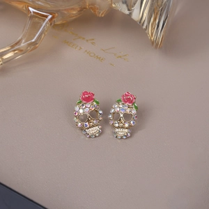 Macro detail of gothic skull earrings with colorful crystals and red roses