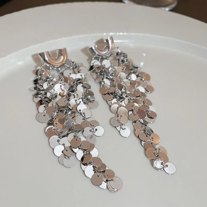 Close-up of silver U-shaped tassel earrings with shimmering metal sequins and long fringe