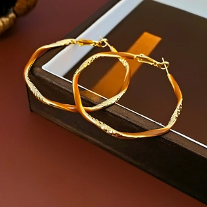 Macro detail of golden twist textured metal hoop earrings on a vintage jewelry box