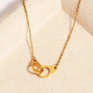 Dettaglio della collana con manette d'oro e incisione Freedom su velluto