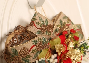 Detail of Christmas heart ribbon wreath with poinsettia, pine cones and rustic burlap bow