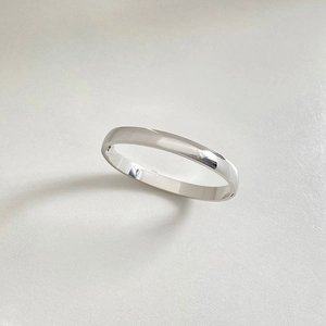 Detailed view of polished silver stainless steel bangle on a minimalist white background