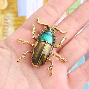 Detailed view of beetle brooch with green enamel and gold-tone zinc alloy texture