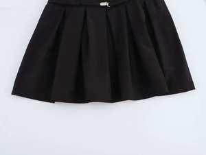Detail van de zwarte geplooide jurk met metalen gesp in de taille en luxe stoffen