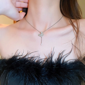 Silver necklace with zircon butterfly and teardrop pendant worn by model in black outfit