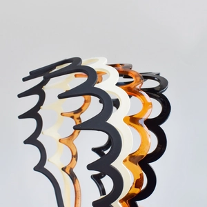 Close-up of four wavy toothed headbands in black, white, and amber leopard patterns