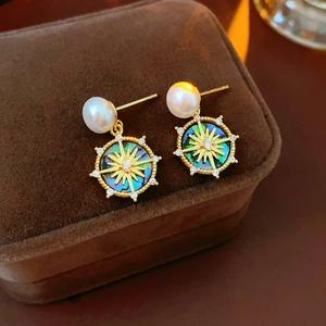 Close-up of gold-plated earrings featuring white pearl and abalone shell star motifs