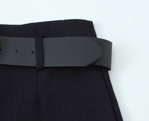 Detail of black leather belt on tailored twill shorts with gold button accents