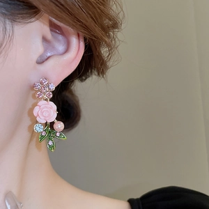 Macro detail of pink flower earring with diamonds and pearls worn on a model