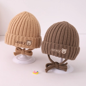 Detail of warm baby knit earflap hats with lucky embroidery and bear patches