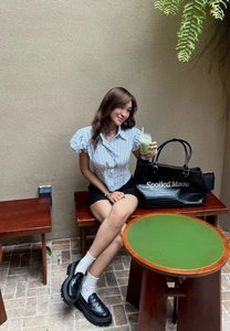 Outdoor street view of a blue striped puff sleeve shirt styled with a black tote bag