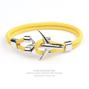 Close-up of a yellow woven bracelet with a polished silver aircraft-shaped metal clasp