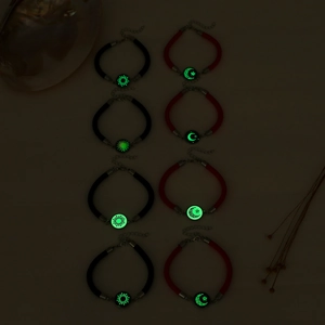 Nahaufnahme leuchtender Sonnen- und Mondanhänger an gewebten Armbändern mit grünem Effekt