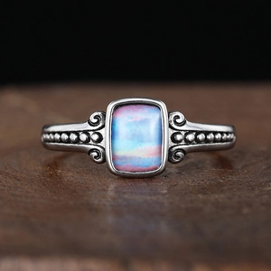 Macro detail of teardrop vintage silver ring with rectangle rainbow stone and filigree