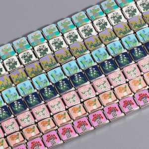 Macro detail of Italian charm links with floral enamel patterns on stainless steel