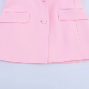 Detailed view of pink woven fabric with fabric-covered button and symmetrical flap pockets
