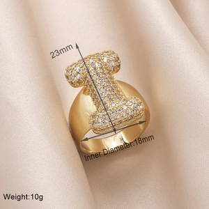 Detail view of gold letter I ring with cubic zirconia on beige silk including dimensions