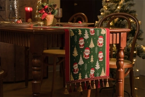 Close-up of festive green Christmas table runner with Santa patterns and fringe detail