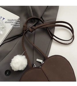 Detail der dunkelbraunen Herzform Ledertasche mit Silberreißverschluss und weißem Fellanhänger