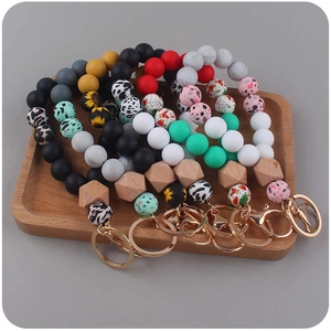 Assorted silicone and wood bead keychains with leopard and floral prints on wooden tray