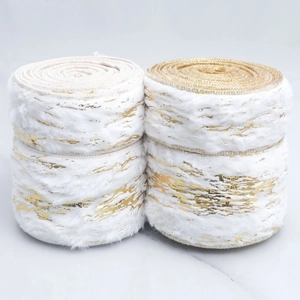 Close-up of four rolls of white plush ribbon with gold foil patterns for DIY crafts