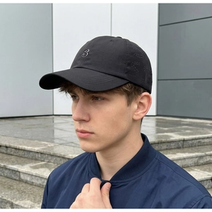 Close-up of a men's black baseball cap featuring laser-cut breathable holes and an S logo